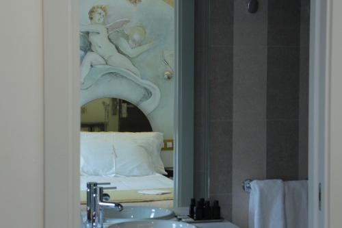 baño con espejo sobre lavamanos y cama en Grecorooms en Toledo