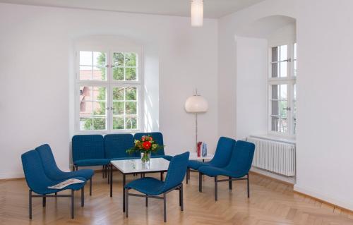 Zimmer mit blauen Stühlen und einem Tisch mit einer Blumenvase in der Unterkunft Akademie der Dioezese Weingarten in Weingarten