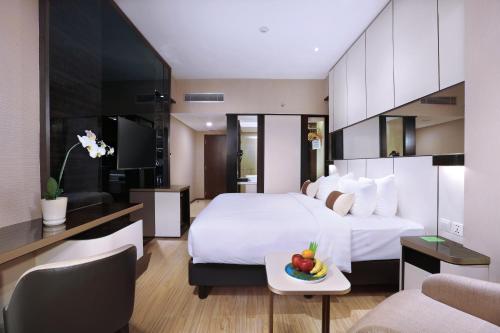 a hotel room with a bed with a bowl of fruit on a tray at The Alts Hotel in Palembang