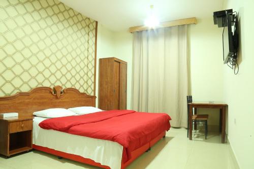 a bedroom with a bed with a red blanket at Emirates Plaza Hotel in Ajman 