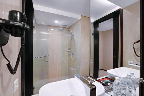 a bathroom with a shower and a sink and a mirror at The Alts Hotel in Palembang