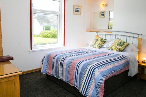 a small bedroom with a bed with a window at The White Heron in Polzeath