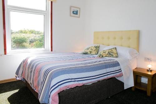 a bedroom with a large bed with a window at The White Heron in Polzeath