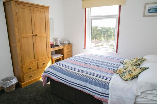 a bedroom with a bed and a dresser and a window at The White Heron in Polzeath