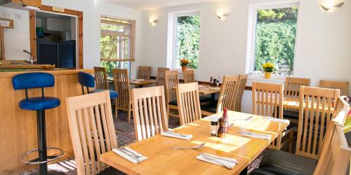 a restaurant with wooden tables and chairs and windows at The White Heron in Polzeath