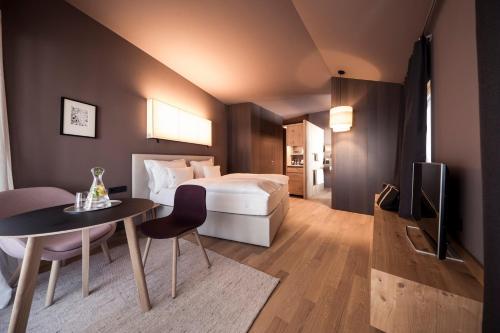 a hotel room with a bed and a table and a television at Hotel Lamm in Castelrotto