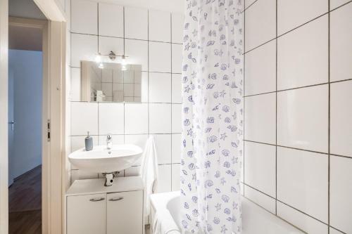 a white bathroom with a sink and a shower curtain at Work & stay apartments DD in Düsseldorf