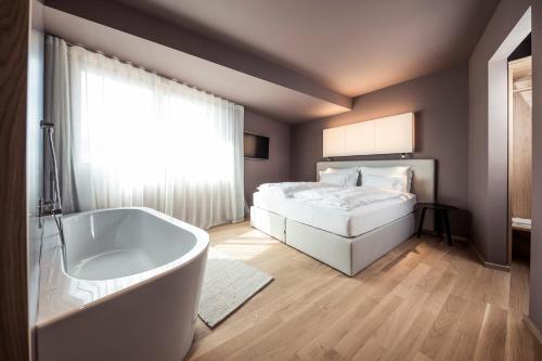a bedroom with a tub and a bed and a window at Hotel Lamm in Castelrotto