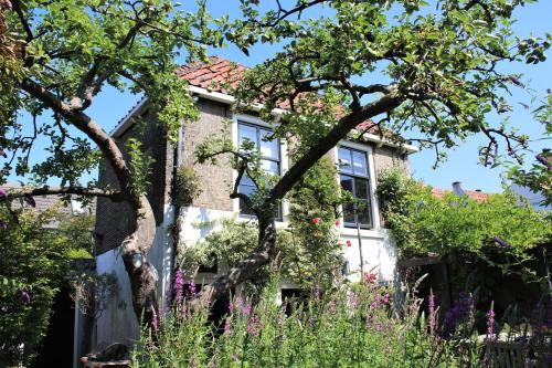 a house with flowers in front of it at Apple Tree Cottage - charming home at beautiful canal in our idyllic garden in Gouda