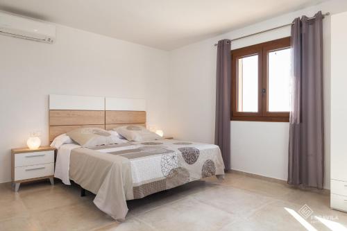 a white bedroom with a bed and a window at Moli den Sion in Sa Pobla