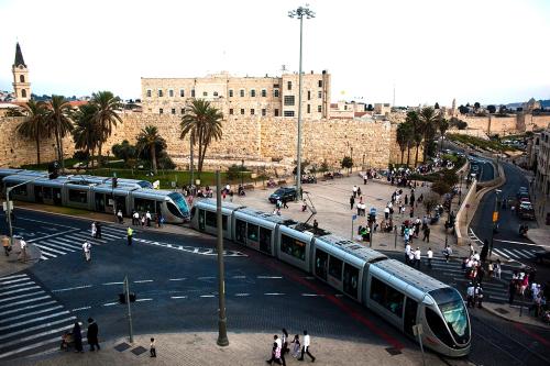 a train on a street in a city with people at Mamilla Design Apartments in Jerusalem