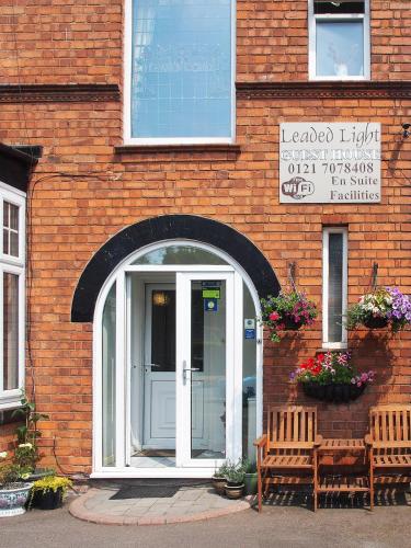 a brick building with a door and two benches at Leaded Light Guest House in Solihull
