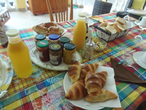 a table with a plate of pastries and orange juice at Villa Mancina in Capesterre-Belle-Eau