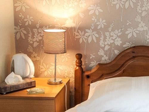 a bedroom with a bed and a lamp on a table at Leaded Light Guest House in Solihull