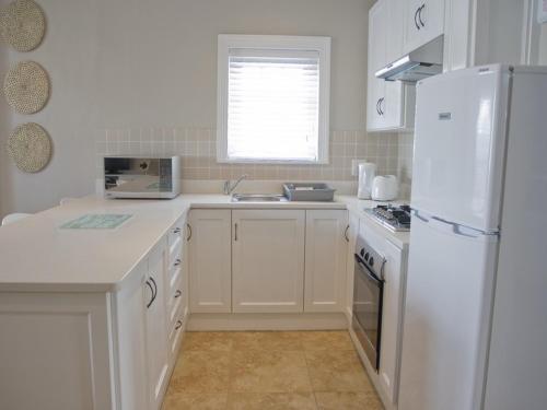 a kitchen with white cabinets and a white refrigerator at Kenjockity Self Catering Apartments in Hermanus