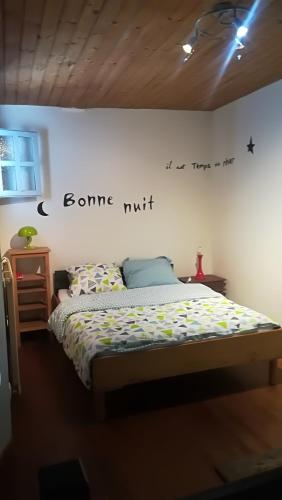 une chambre avec un lit avec un panneau sur le mur dans l'établissement Gîte de Lolotte et Gégé, à Audeux