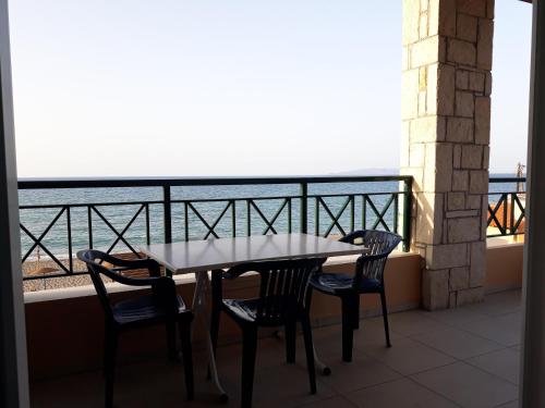Minoica Beach Apartments في أمودارا هيراكليو: طاولة وكراسي على شرفة مطلة على المحيط