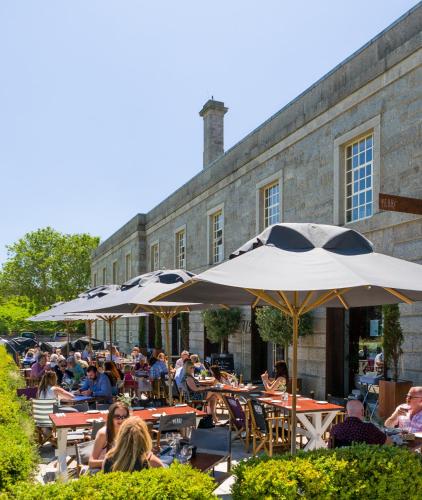 people sitting at tables with umbrellas in front of a building at Admiral's House by Maison Pierre in Plymouth