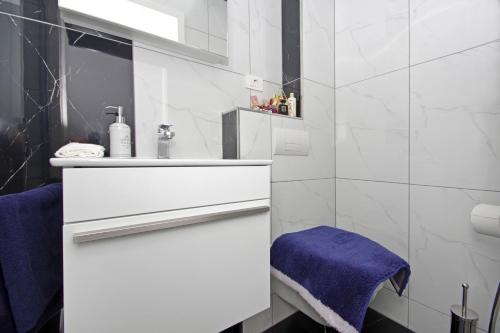a white bathroom with a sink and a blue towel at Villa Inis in Makarska
