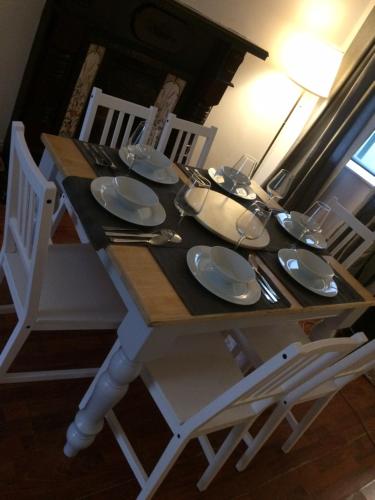 una mesa de madera con sillas y platos blancos. en Danny’s Place, en Derry Londonderry