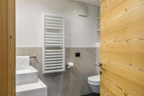 y baño con aseo blanco y lavamanos. en Residence Rottonara, en Corvara in Badia