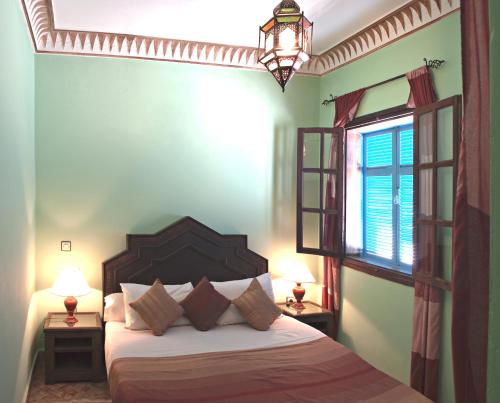 a bedroom with a bed with two lamps and a window at Riad Maison Du Sud in Essaouira
