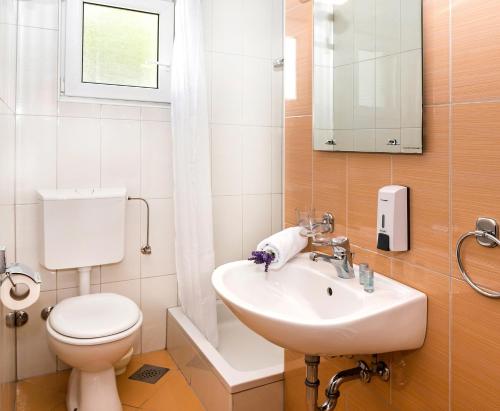 a white bathroom with a toilet and a sink at Apartmani Lučica in Mimice