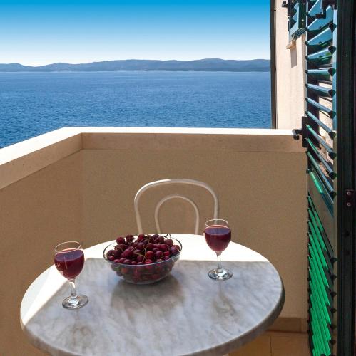 a table with two glasses of wine and a bowl of fruit at Apartmani Lučica in Mimice