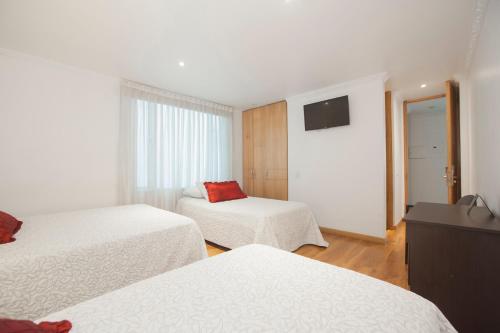 a hotel room with two beds and a television at Hotel Casa Mahanaim Colferias, Bogotá in Bogotá