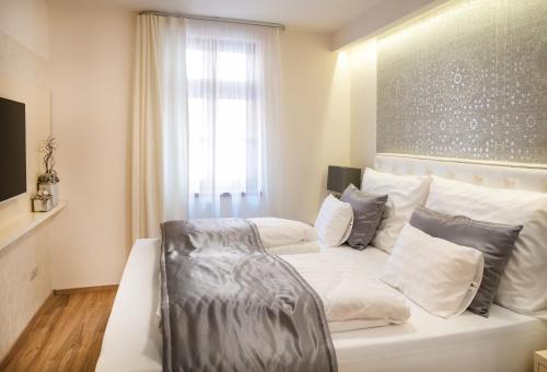 a bedroom with a white bed with pillows and a window at Főtér Rezidencia 2 in Győr