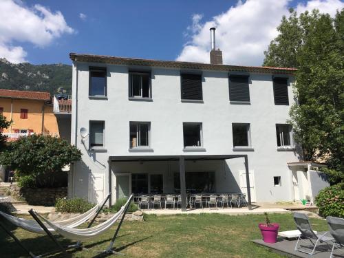 a large white building with chairs in a yard at L'Xpérience in Valgorge