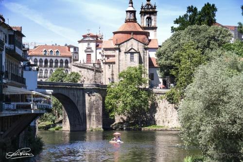 a person in a boat on a river with a bridge at Prestige Apartment in Amarante