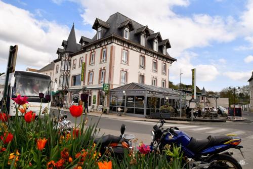 a motorcycle parked in front of a building with flowers at Hotel De Normandie in Arromanches-les-Bains