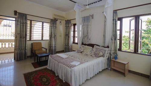 a bedroom with a bed with white sheets and windows at Platinum Hotels Mombasa in Shanzu