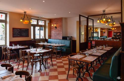 a restaurant with tables and chairs in a room at Hotel De Normandie in Arromanches-les-Bains