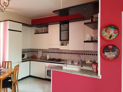 una cucina con armadietti bianchi e parete rossa di Domus lungo ticino a Pavia