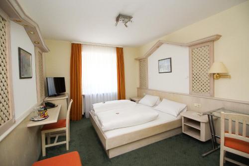 a bedroom with a bed and a desk and a television at Hotel Leopold in Munich