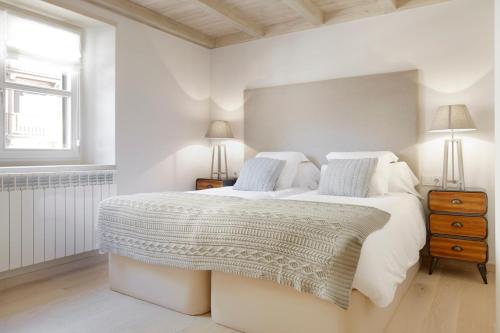 a white bedroom with a large bed and a window at Val de Ruda Luxe 52 by FeelFree Rentals in Naut Aran