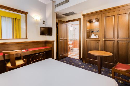 ボローニャにあるベスト ウエスタン シティ ホテルのベッド、テーブル、椅子が備わるホテルルームです。