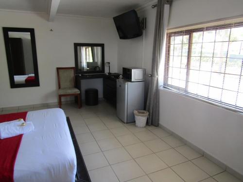 een slaapkamer met een bed, een koelkast en een raam bij Buckleigh Guesthouse in Durban