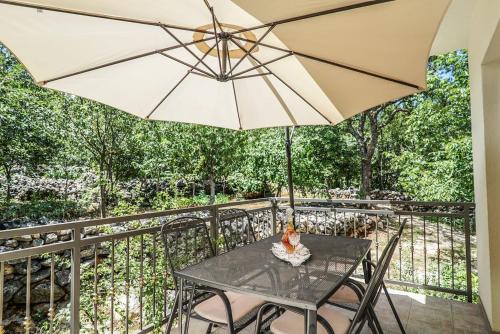 a table and chairs with an umbrella on a balcony at Holiday house between the sea and lakes in Grubine