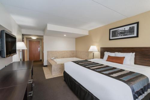 a hotel room with a large bed and a tub at Wingate by Wyndham Bowling Green in Bowling Green
