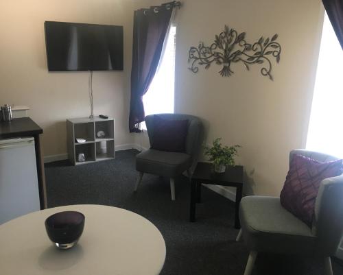 a living room with a table and chairs and a tv at The Crown Hotel in Newton Stewart