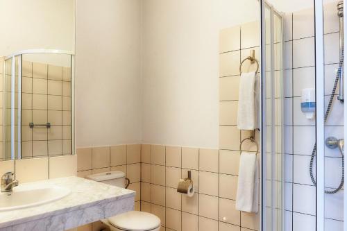 La salle de bains est pourvue de toilettes, d'un lavabo et d'une douche. dans l'établissement Focus Hotel Łódź, à Łódź