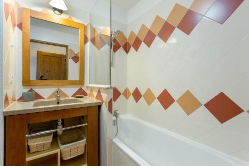 une salle de bain avec une baignoire, un lavabo et un miroir dans l'établissement Apartment Aiglons - Central Chamonix Mountain Haven, à Chamonix-Mont-Blanc