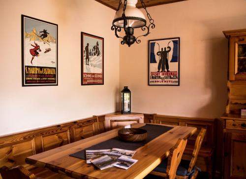 uma sala de jantar com uma mesa de madeira e cartazes na parede em La finestra sulle Dolomiti - The Window to the Dolomites em Fiera di Primiero