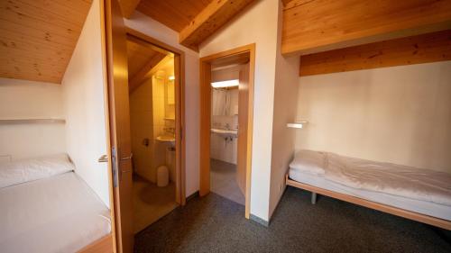 a small room with two beds and a bathroom at Sportchalet Mürren in Mürren