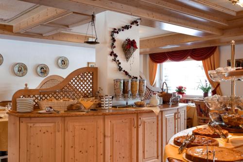 a kitchen with wooden cabinets and a table with dishes at Alpenhotel Panorama in Campitello di Fassa
