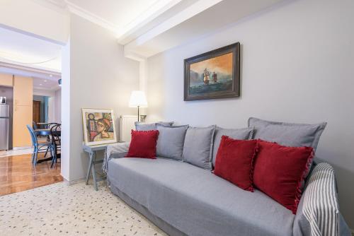 a living room with a gray couch with red pillows at Splash of Glam II 10 Steps from Acropolis in Athens