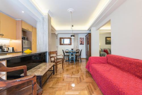 a living room with a red couch and a kitchen at Splash of Glam II 10 Steps from Acropolis in Athens